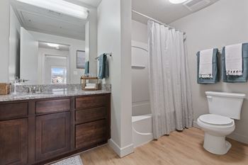 A white toilet sits next to a shower curtain in a bathroom.